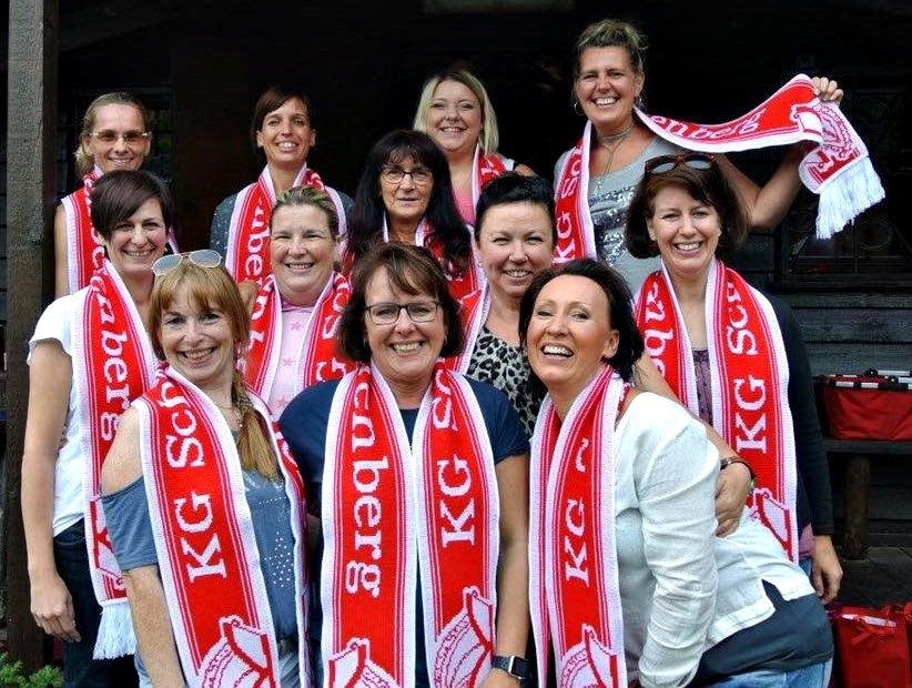 Mitglieder der Showtanzgruppe mit Vereinsschals vor einem Gebäude